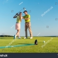 stock-photo-full-length-of-a-skilled-golf-instructor-teaching-a-young-woman-to-swing-the-driver-club-for-a-1116629534 